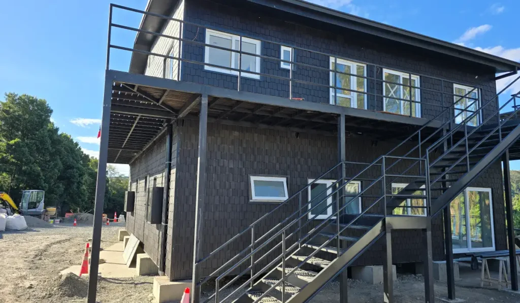 Fachada terminada de edificio modular con tejuela plástica negra